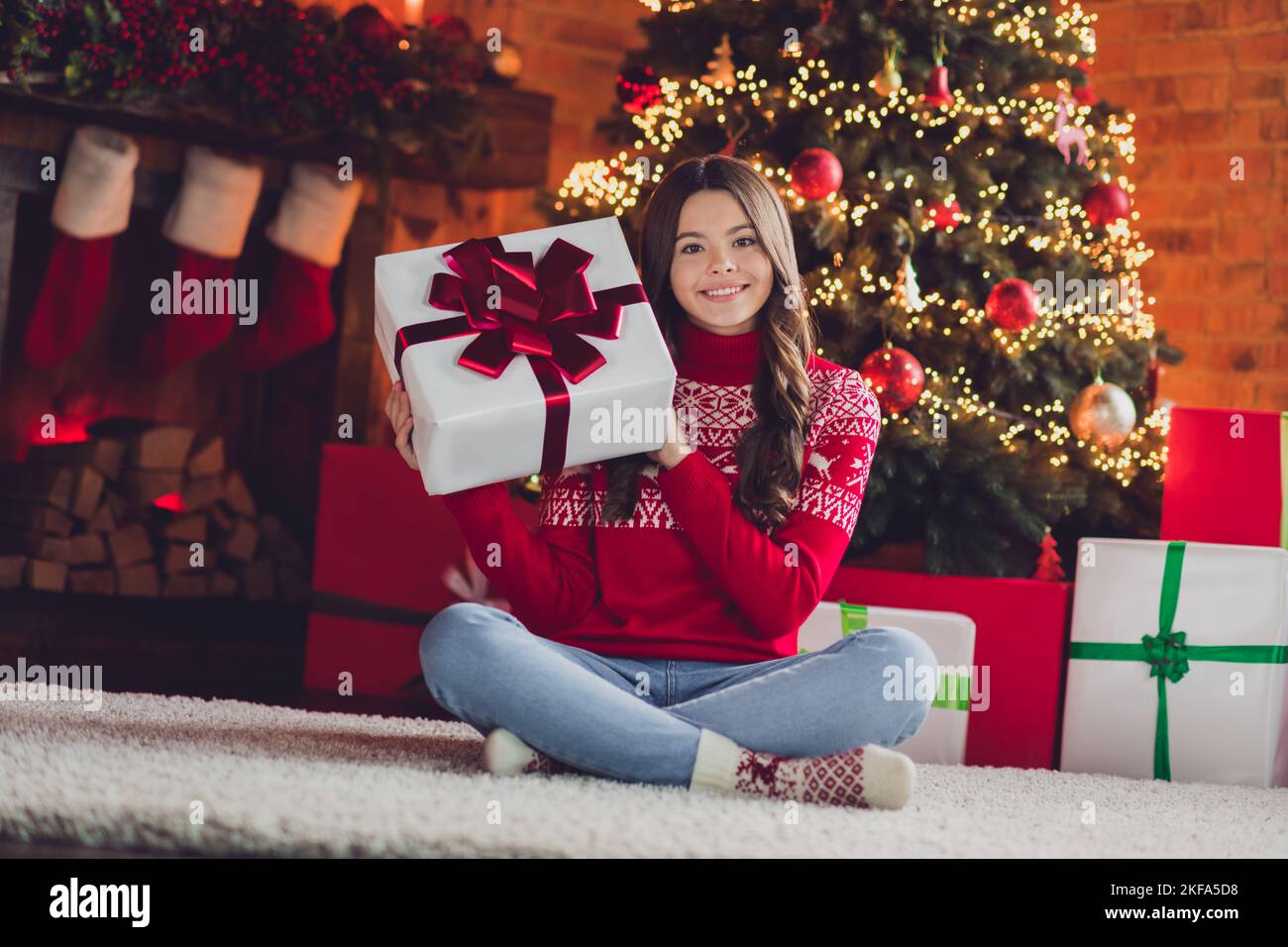 Photo of pretty joyful lady teen sit fluffy carpet floor show santa claus gift box package rejoice good time enjoy day room house indoors Stock Photo