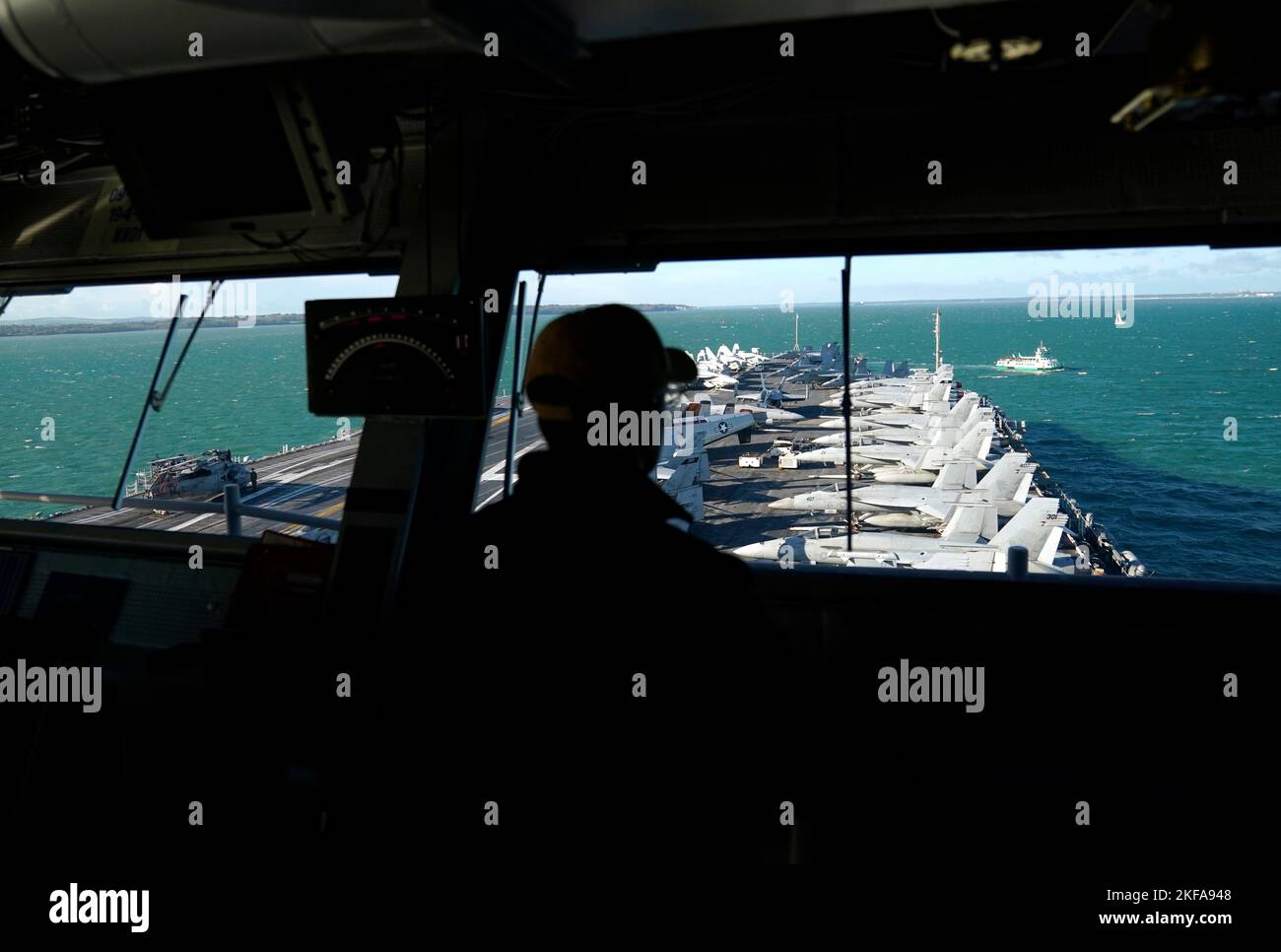 A person on the bridge looks down at F18 jets lined up on the flight ...
