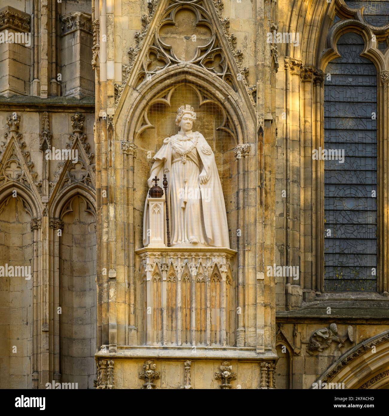 Elizabeth 2 limestone statue standing on high niche wearing ceremonial dress (orb & sceptre) - west front, York Minster, North Yorkshire, England, UK. Stock Photo