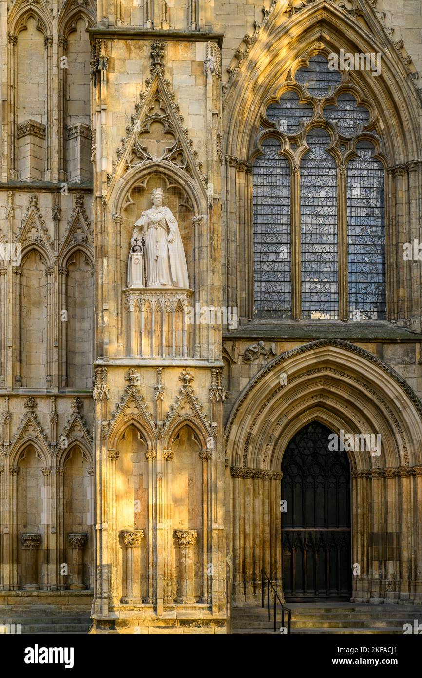 Elizabeth 2 limestone statue standing on high niche wearing ceremonial dress (orb & sceptre) - medieval York Minster, North Yorkshire, England UK. Stock Photo