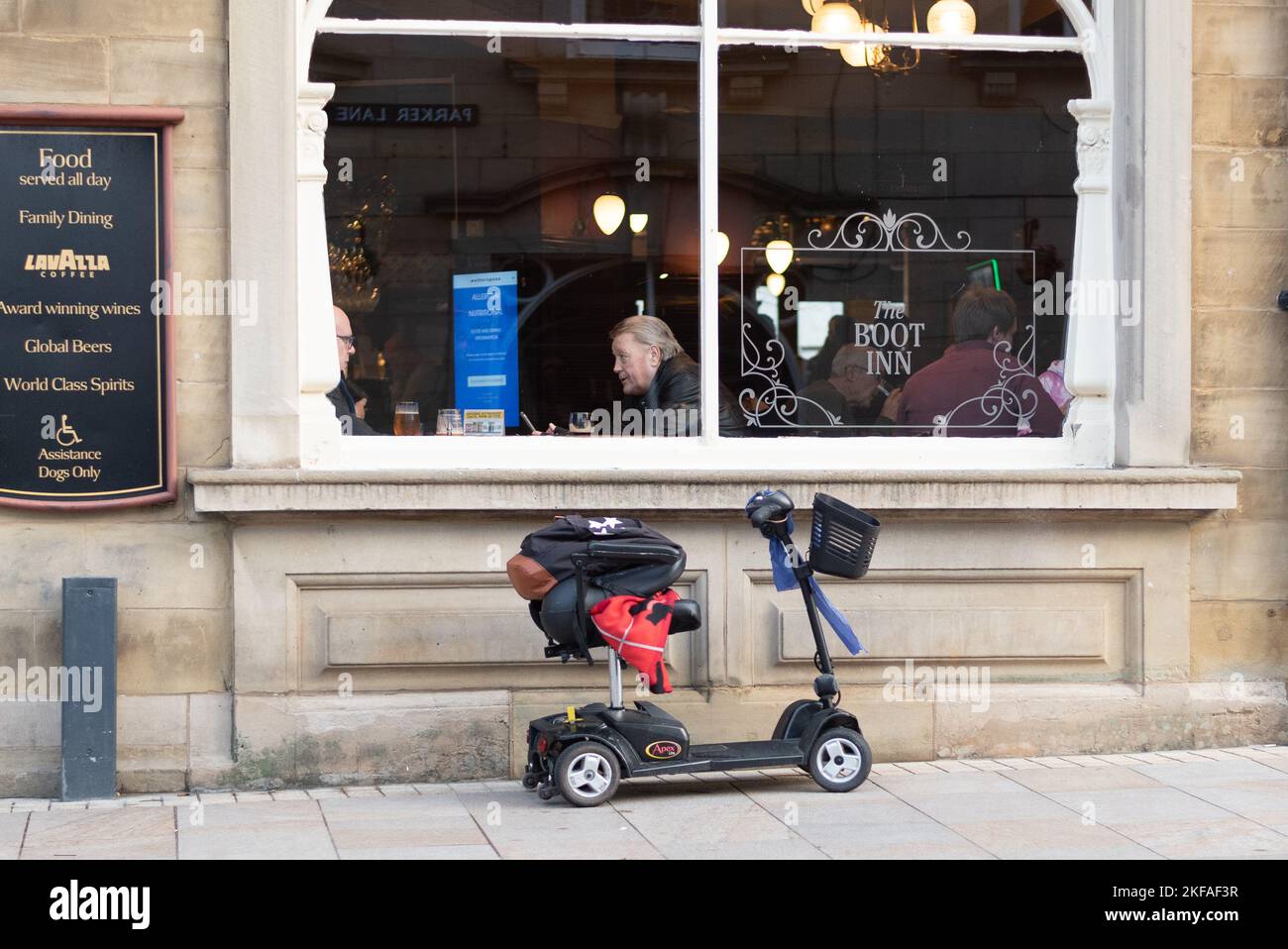 Mobility Scooter outside Pub in Burnley Town Centre with men sat in the window Stock Photo