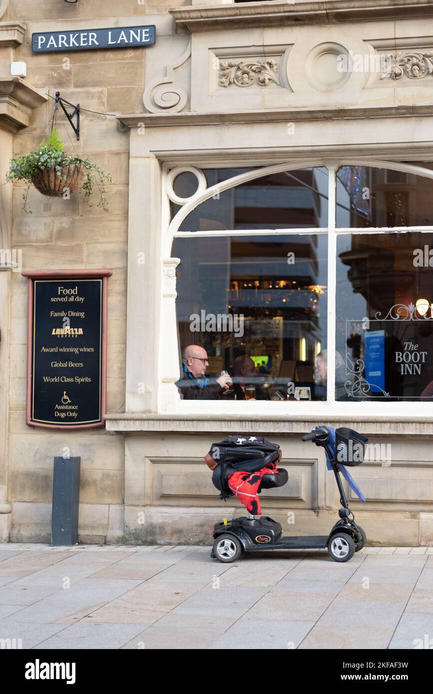 Mobility Scooter outside Pub in Burnley Town Centre with men sat in the window Stock Photo