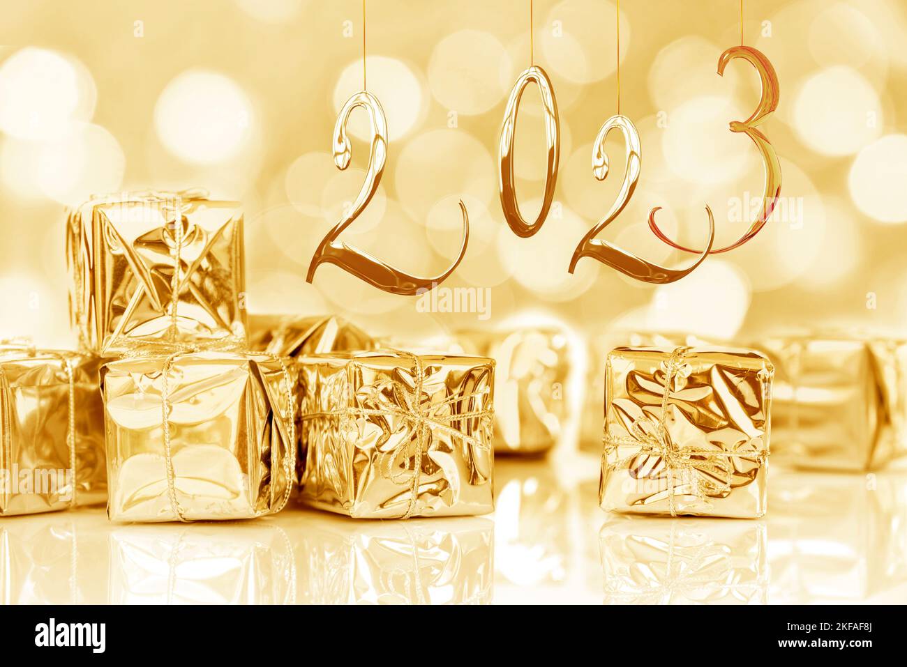 2023, new year card. Small Christmas gifts in shiny golden paper, bokeh lights background Stock Photo