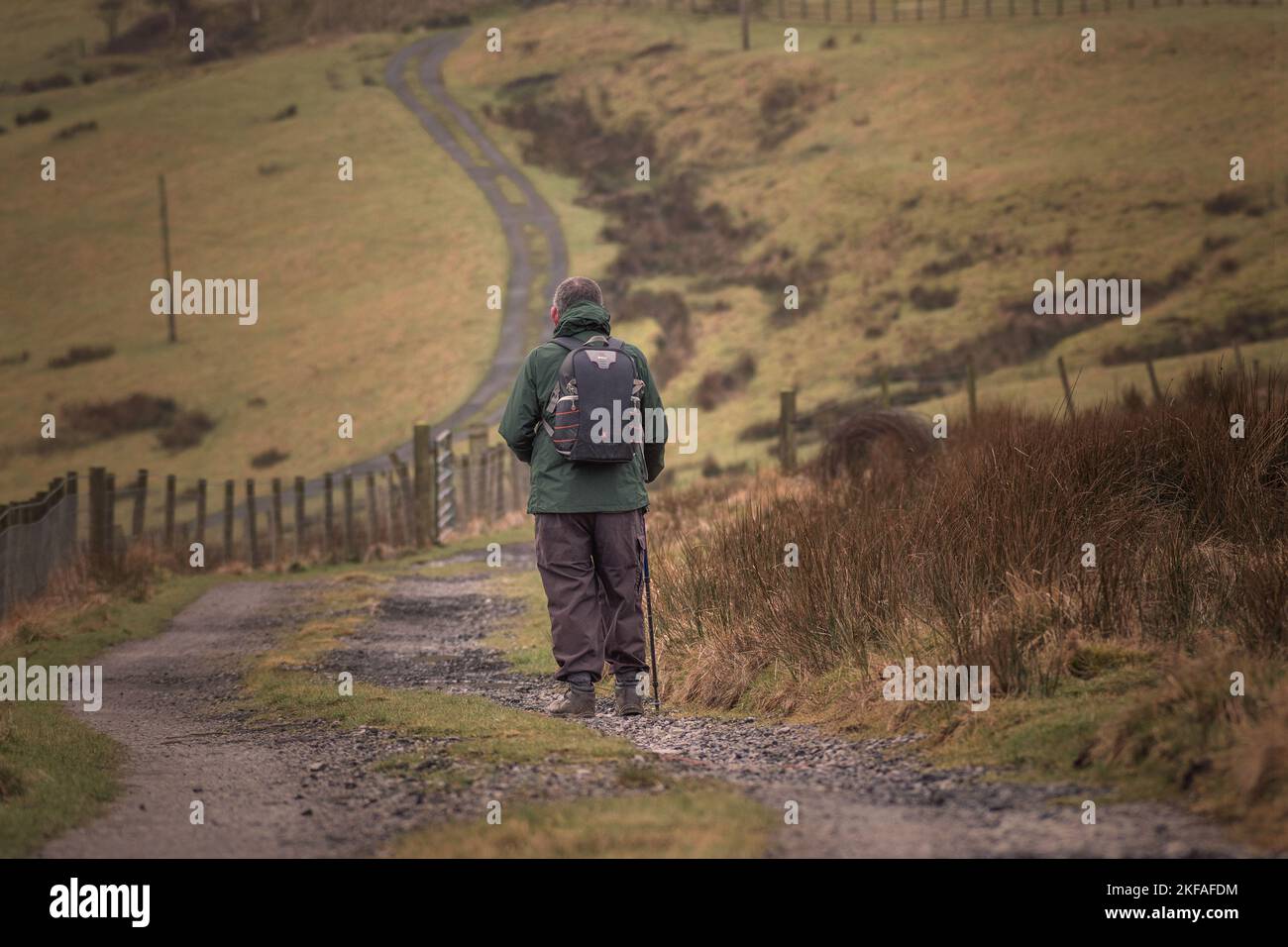 Senior citizen walking and exercising in the countryside. Walking with walking stick on the moorland path. Stock Photo
