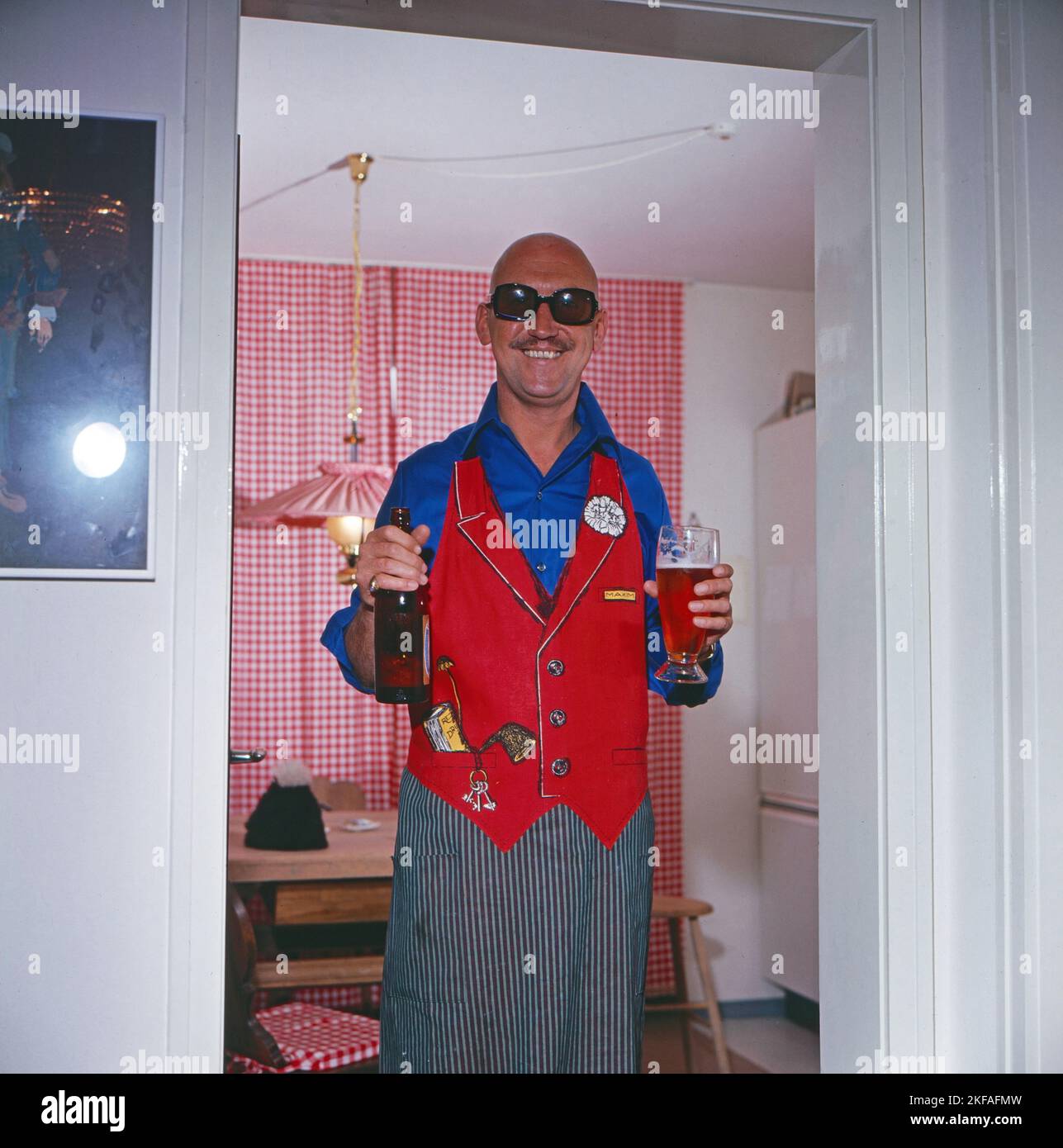 Karl Lieffen, deutscher Bühnen-, Fernseh- und Filmschauspieler, in Schürze mit einem Bier, Deutschland um 1979. Stock Photo