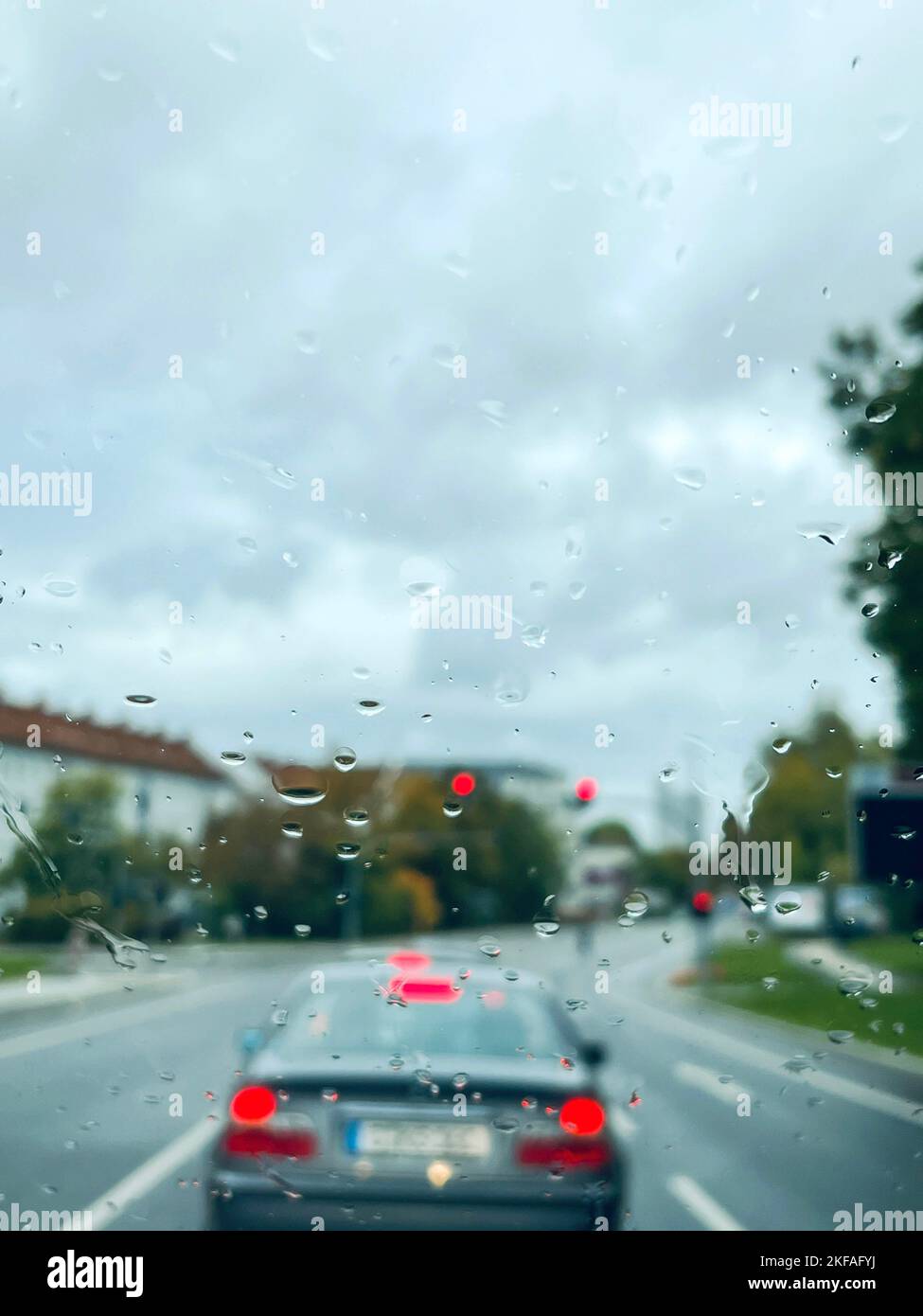 raining, rain drops on window of a car over road with traffic in a