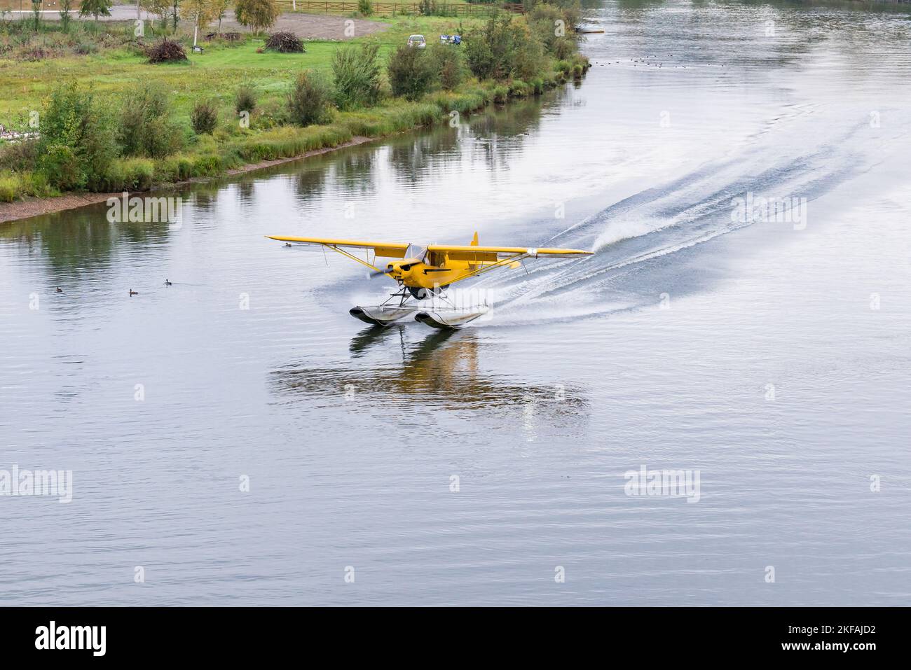 Yellow bush float plane landing on the Chena River in Alaska Stock Photo