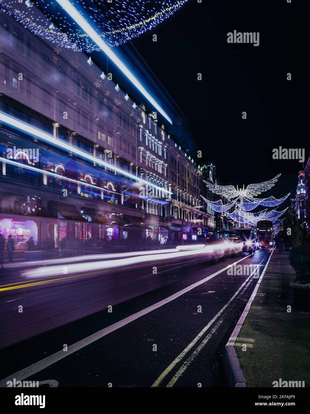 Traffic pass by Hamley's toy store with the golden angel christmas decorations on Regent Street in London. Stock Photo