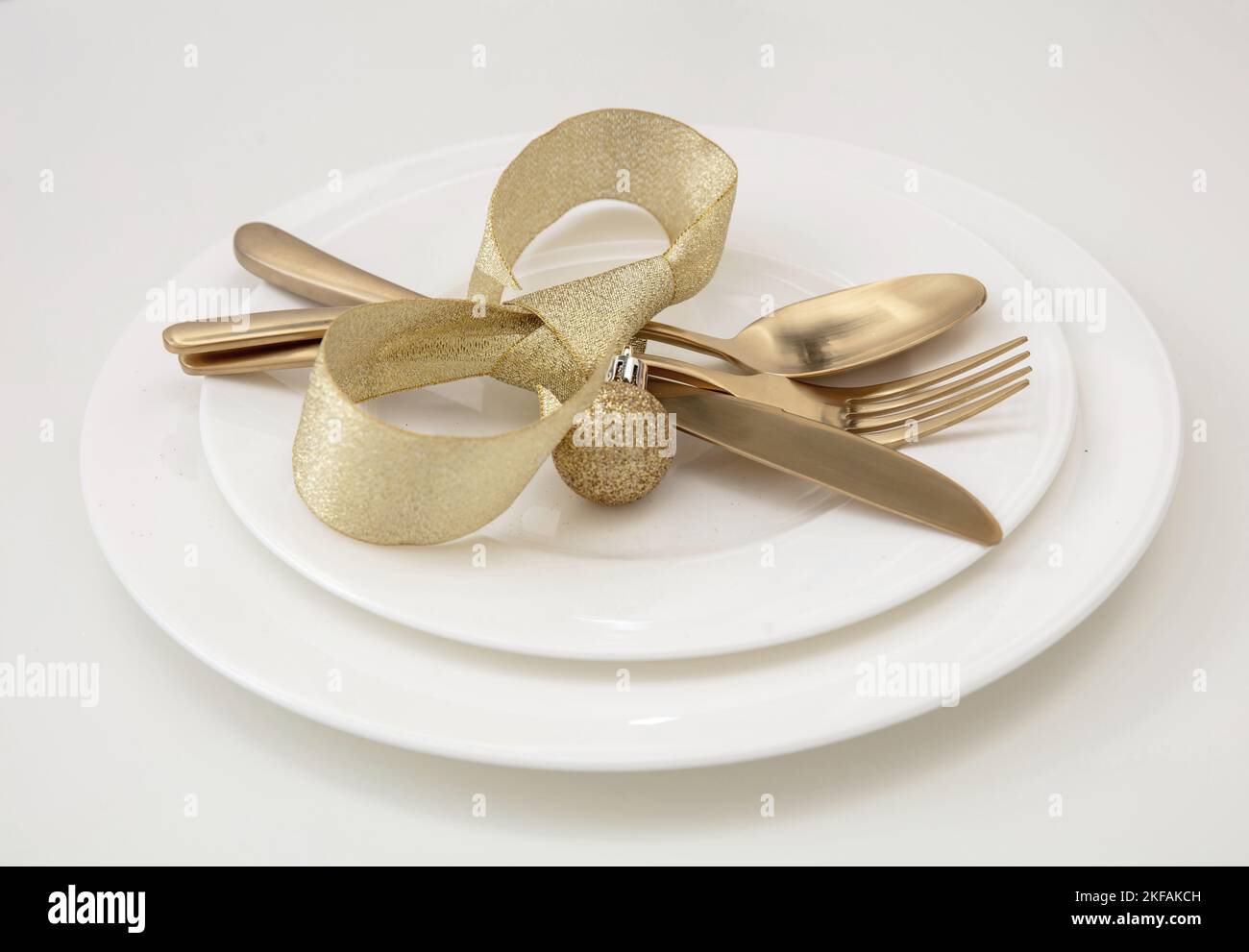 Christmas table setting close up view. Golden cutlery and dishes isolated on white, Elegant restaurant, celebration dinner Stock Photo
