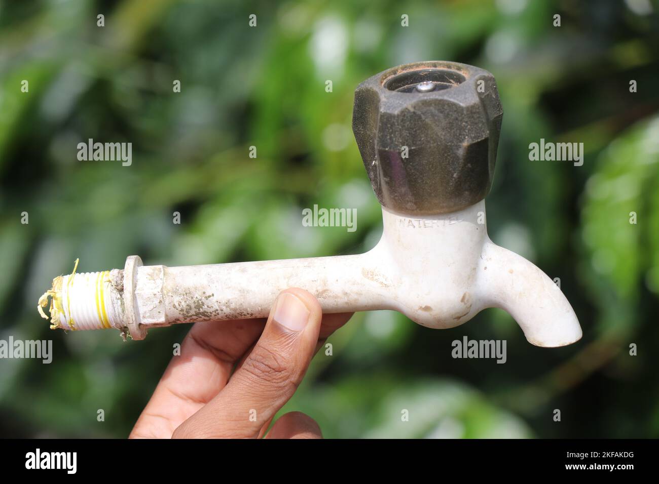 Old water tap or kitchen faucet held in hand on outdoors with natural background Stock Photo