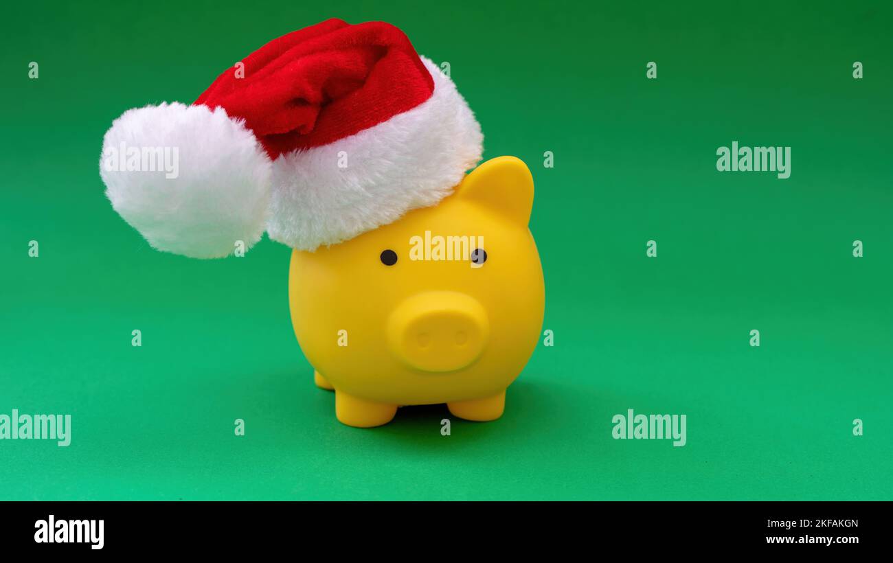 Christmas holiday Sale. Piggy bank with Santa hat isolated on green color background. Stock Photo