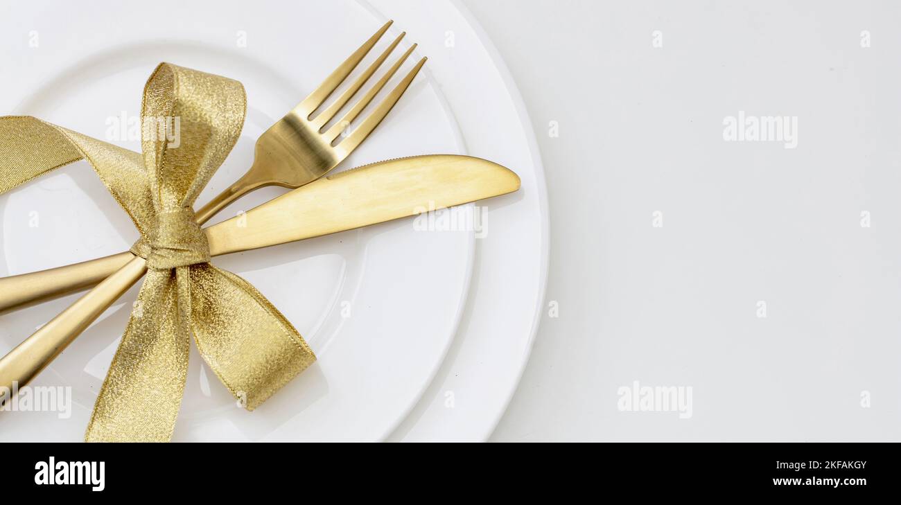 Christmas table setting close up view. Golden cutlery and decoration on white dishes, copy space, top view. Elegance and luxury Stock Photo