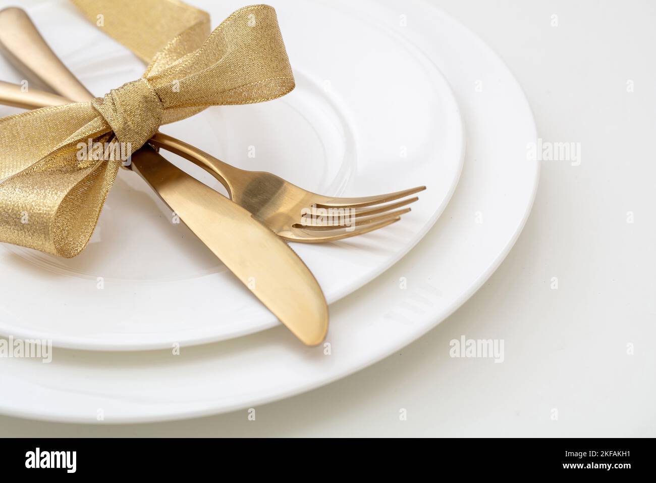 Christmas table setting close up view. Gold cutlery and decoration on white dishes, Elegant restaurant, celebration dinner Stock Photo