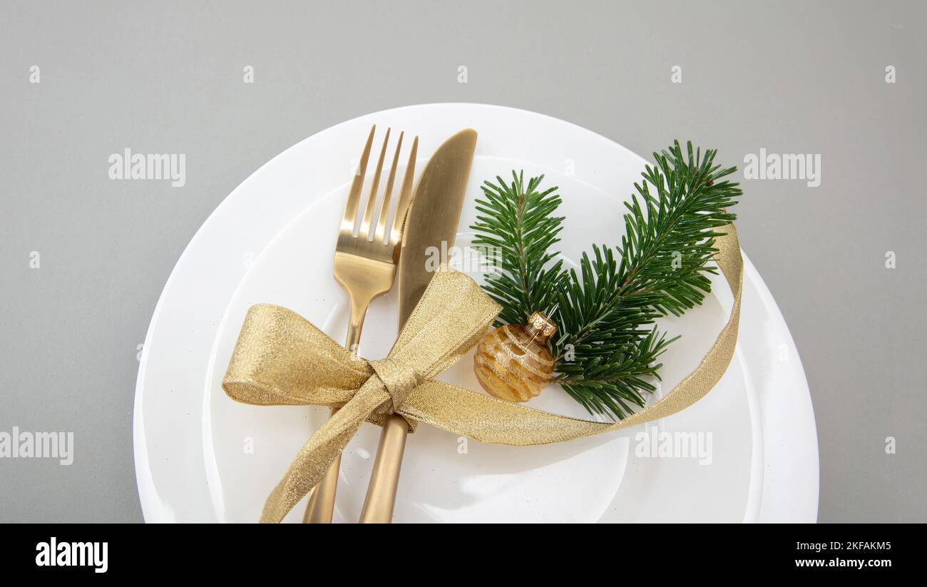 Christmas table setting top view. Gold cutlery and fir decoration on white dishes, New Year celebration dinner Stock Photo