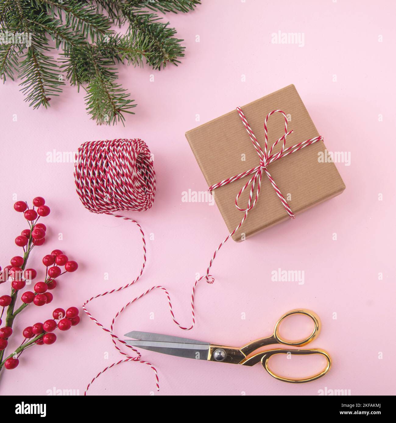 Christmas background. Xmas presents wrapping, gold scissors and ribbon on pink color, top view. Stock Photo