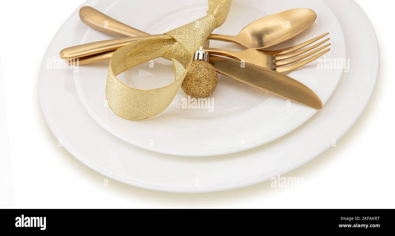 Christmas table setting close up view. Golden cutlery and decoration on white dishes, Elegant restaurant, celebration dinner Stock Photo