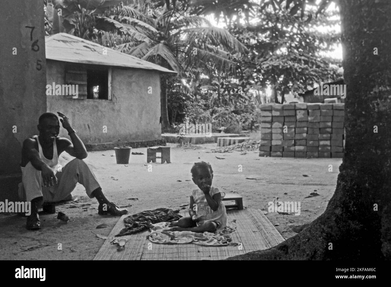 Mann und Kleinkind in einem Innenhof in Sekondi-Takoradi, Ghana, 1959. Man and toddler sitting in the patio in Sekondi-Takoradi, Ghana, 1959. Stock Photo