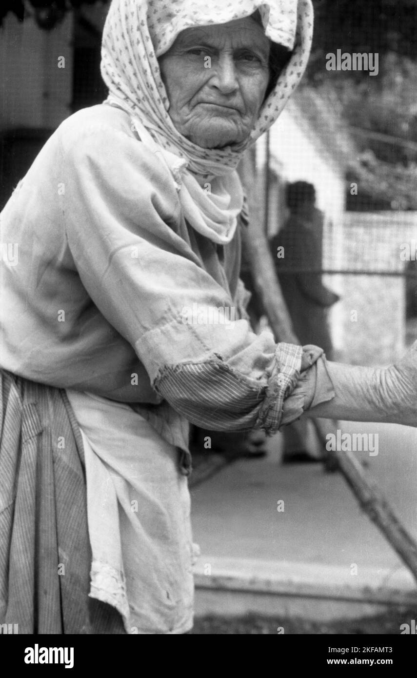 Porträt einer alten Frau mit Kopftuch, Stock und Kittel in Griechenland, 1950er Jahre. Portrait of an old woman with headscarf, cane and smock in Greece, 1950s. Stock Photo