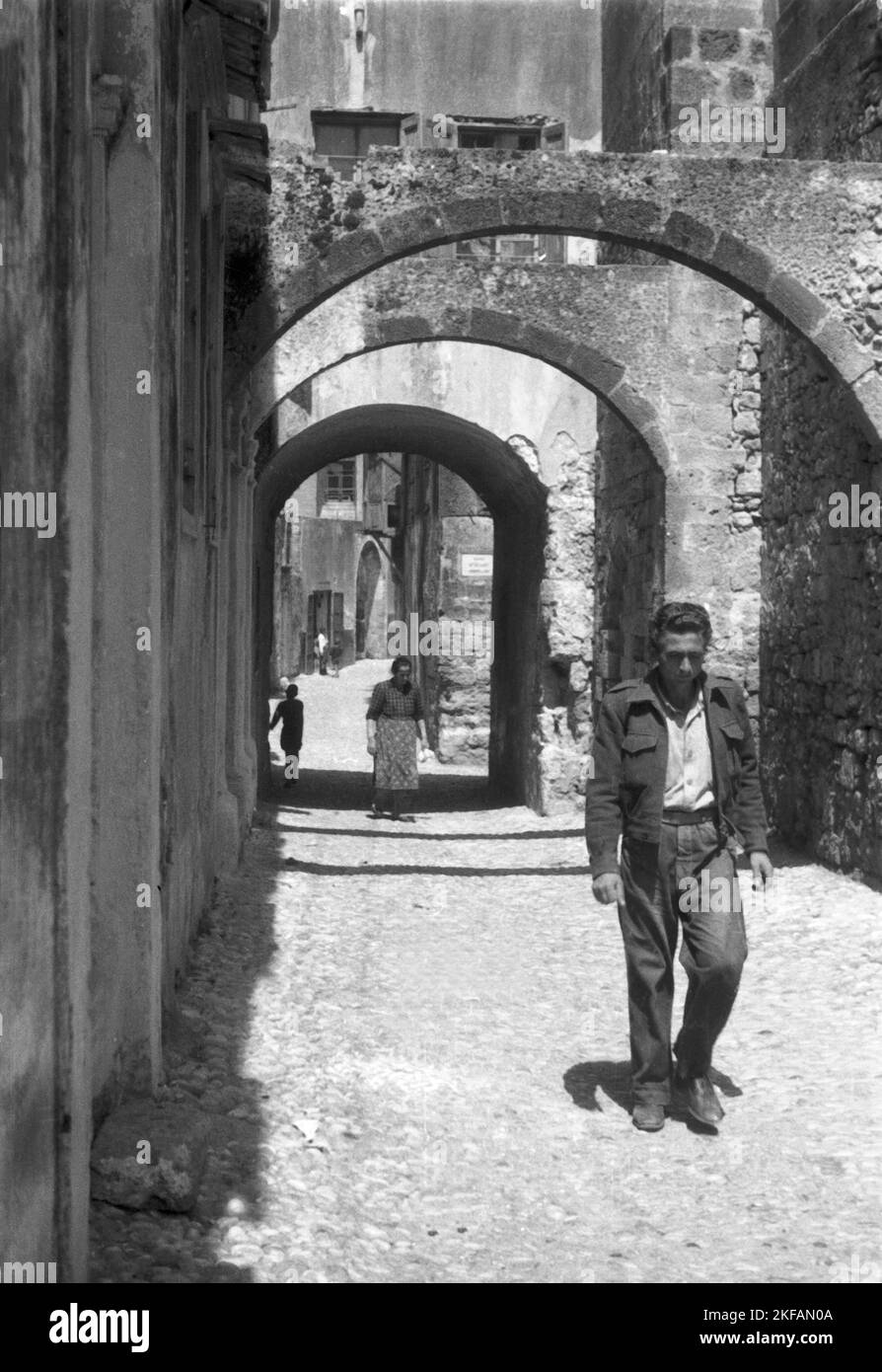 Ein Mann geht durch eine kleine enge Gasse in Griechenland, 1950er Jahre. A man walking through a narrow lane in Greece, 1950s. Stock Photo