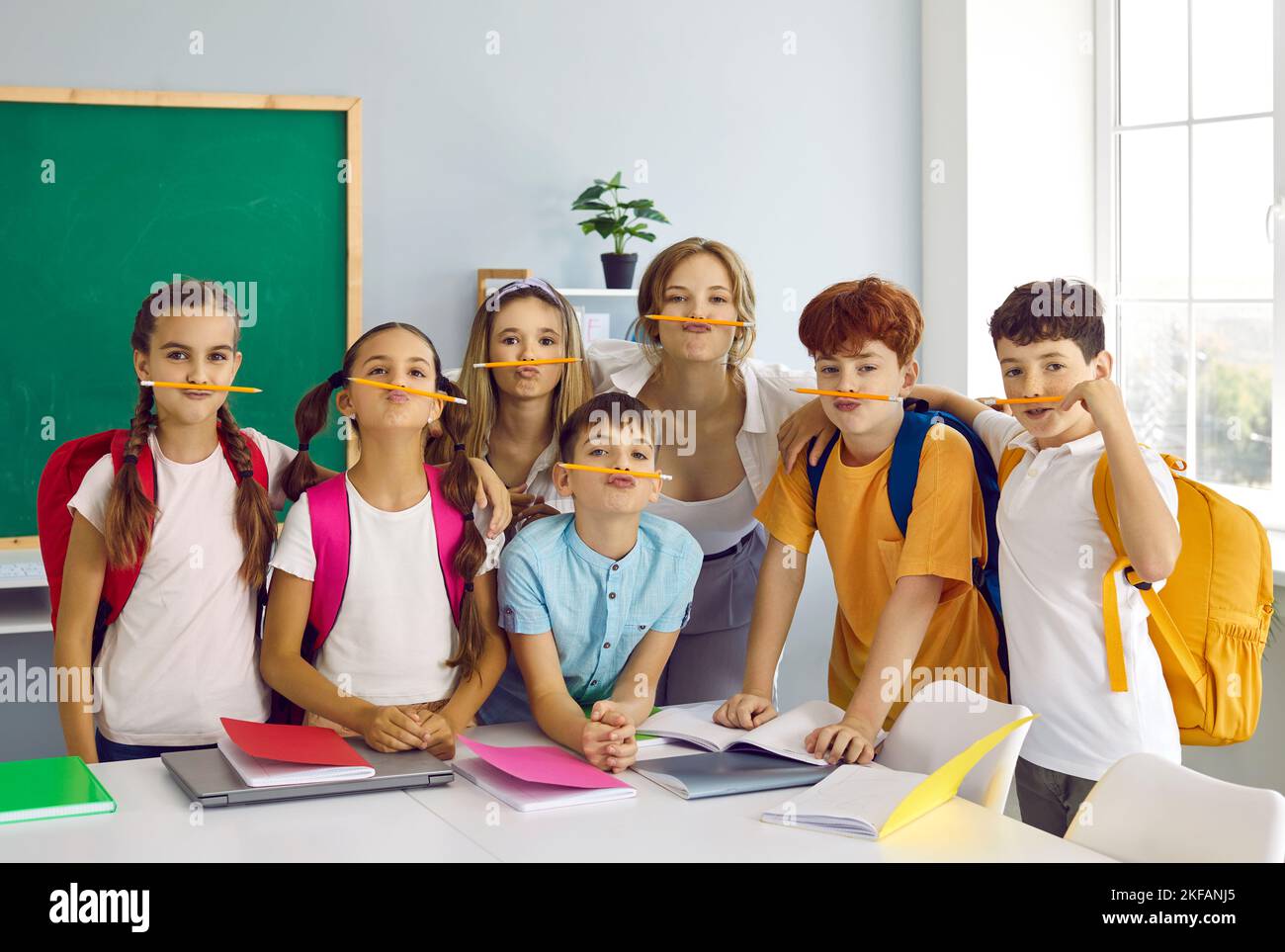 Funny portrait of happy junior school children and teacher with pencil mustaches Stock Photo