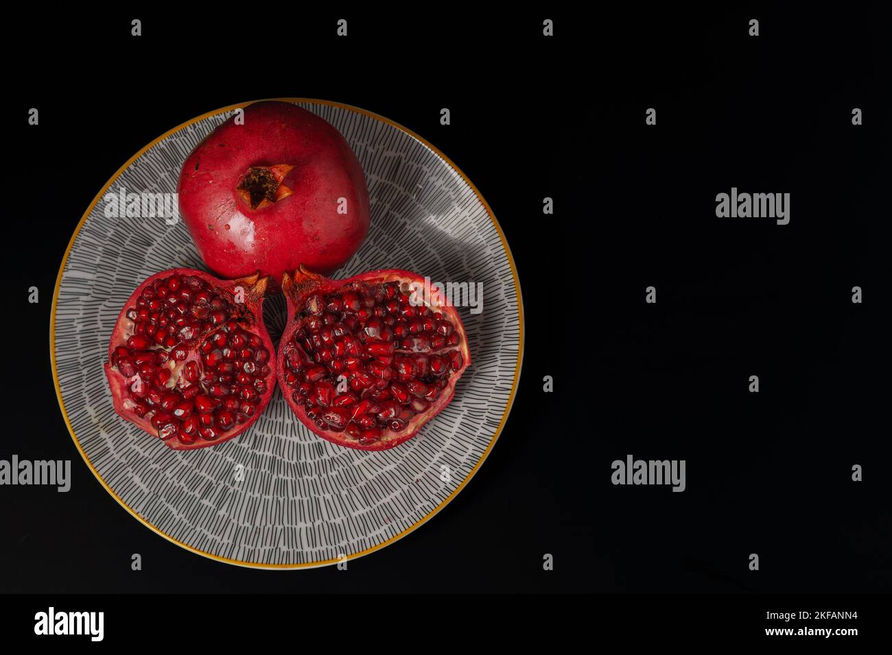 close-up of fresh pomegranate opened on a yellow plate with black ...