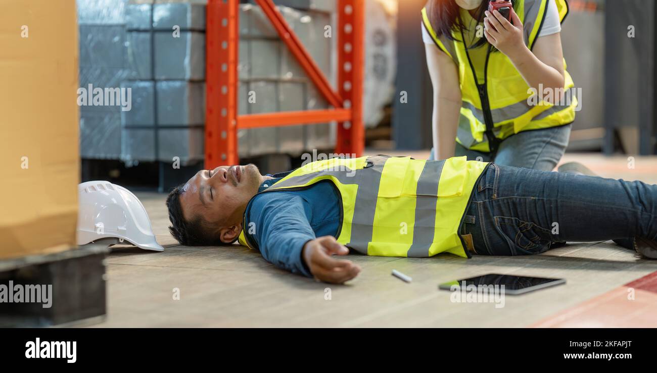 First aid by workmate. Working at warehouse. Male warehouse worker have accident. Stock Photo