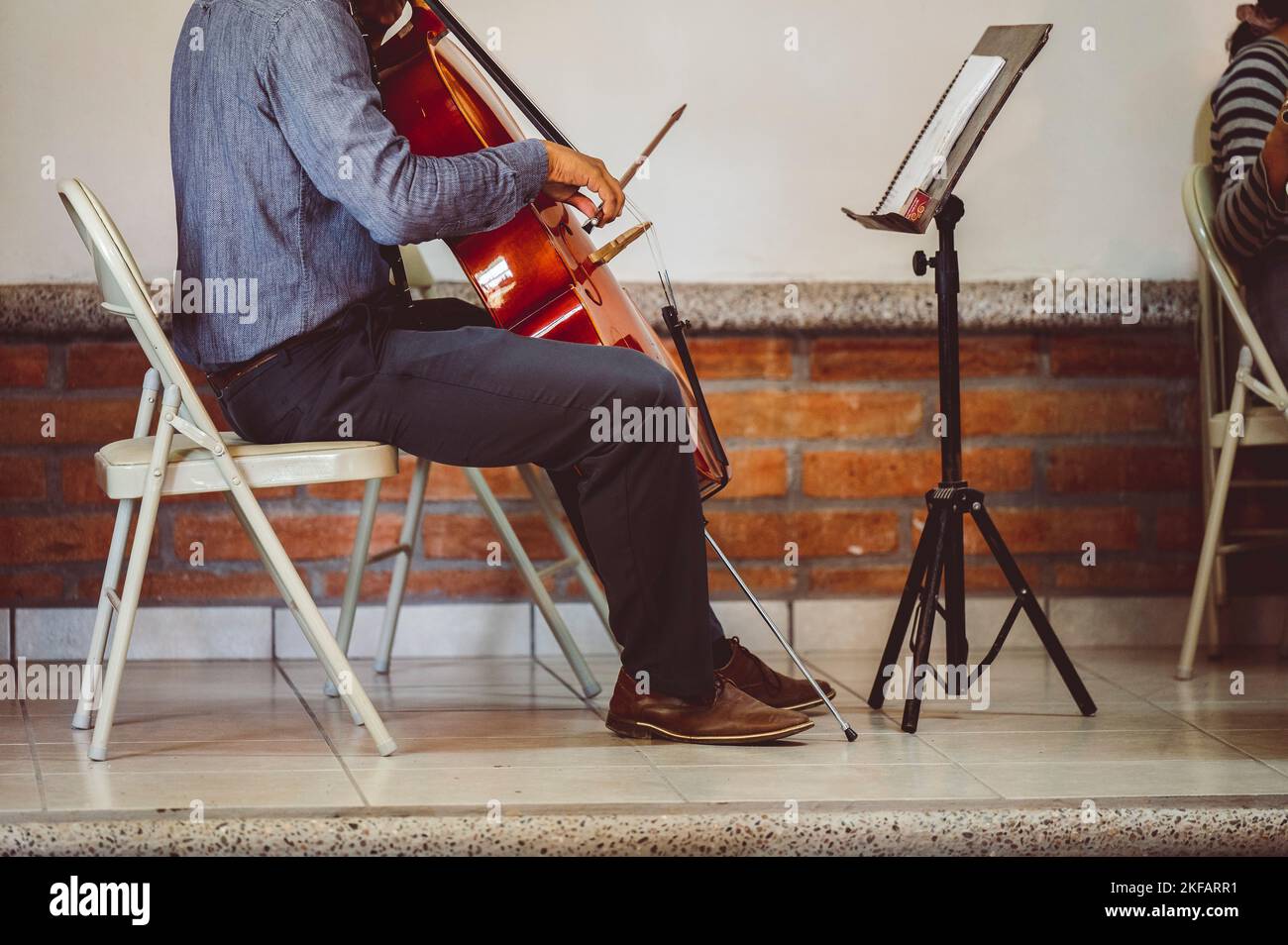 A musician playing cello with musical notes on the book notation stand in front of him Stock Photo