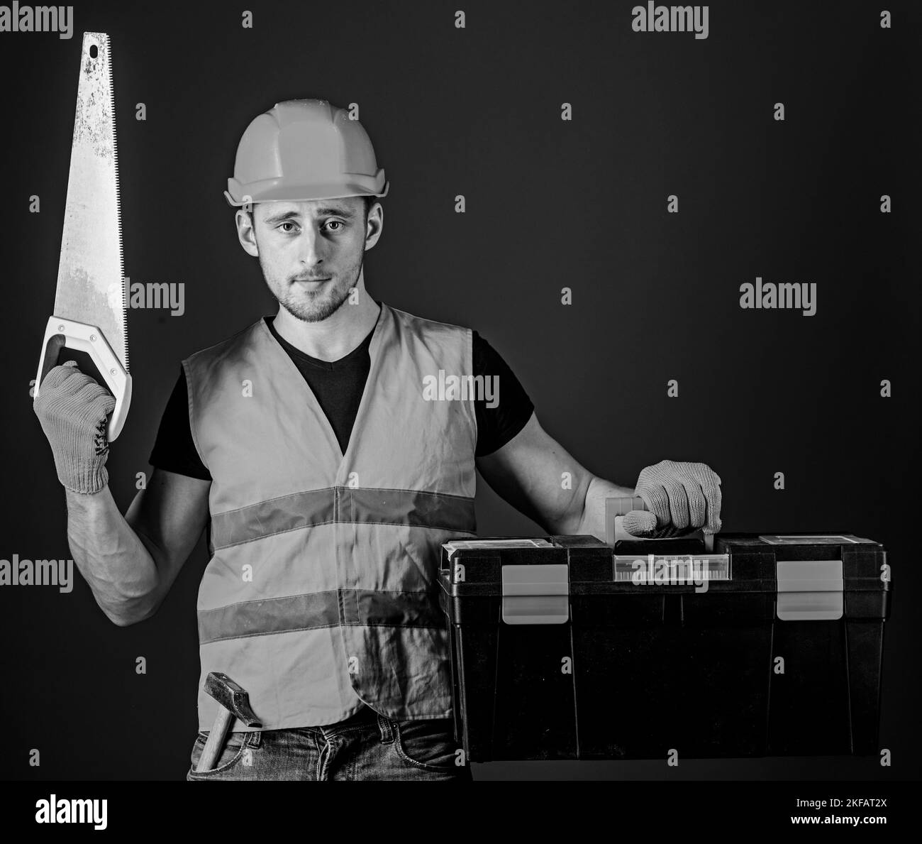 Man in helmet, hard hat carries toolbox and holds handsaw, blue