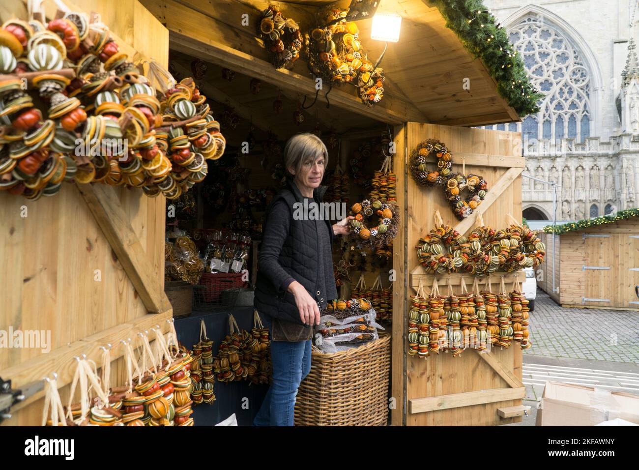 Exeter, UK, 17 November 2022: Vendors are setting up their stalls for the opening of the Exeter Christmas market tomorrow. Clayre, who works for the Devon-based firm Pollyfields, decorates their chalet-style stall with scented dried fruit wreaths. Anna Watson/Alamy Live News Stock Photo