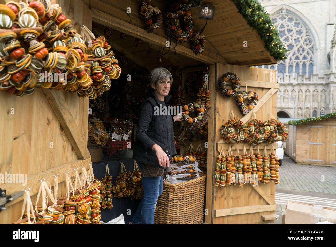 Exeter, UK, 17 November 2022: Vendors are setting up their stalls for the opening of the Exeter Christmas market tomorrow. Clayre, who works for the Devon-based firm Pollyfields, decorates their chalet-style stall with scented dried fruit wreaths. Anna Watson/Alamy Live News Stock Photo