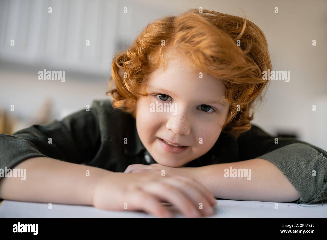 portrait of curly boy with red hair and freckles smiling at camera at home Stock Photo