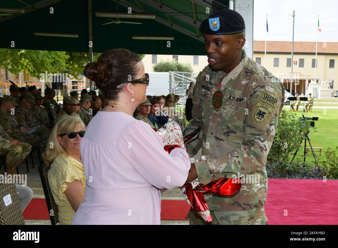 Sgt. 1st Class Timothy Brozell, assigned to the U.S. Army Southern European Task Force, Africa presents a bouquet of red roses, signifying the bonds of appreciation and respect for her dedicated service, to Mrs. Jeanie Gregory, during the SETAF-AF Change of Responsibility Ceremony at Caserma Ederle in Vicenza, Italy, September 1, 2022. Stock Photo