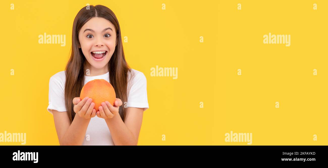 amazed kid hold grapefruit on yellow background, health. Child girl portrait with grapefruit orange, horizontal poster. Banner header with copy space. Stock Photo