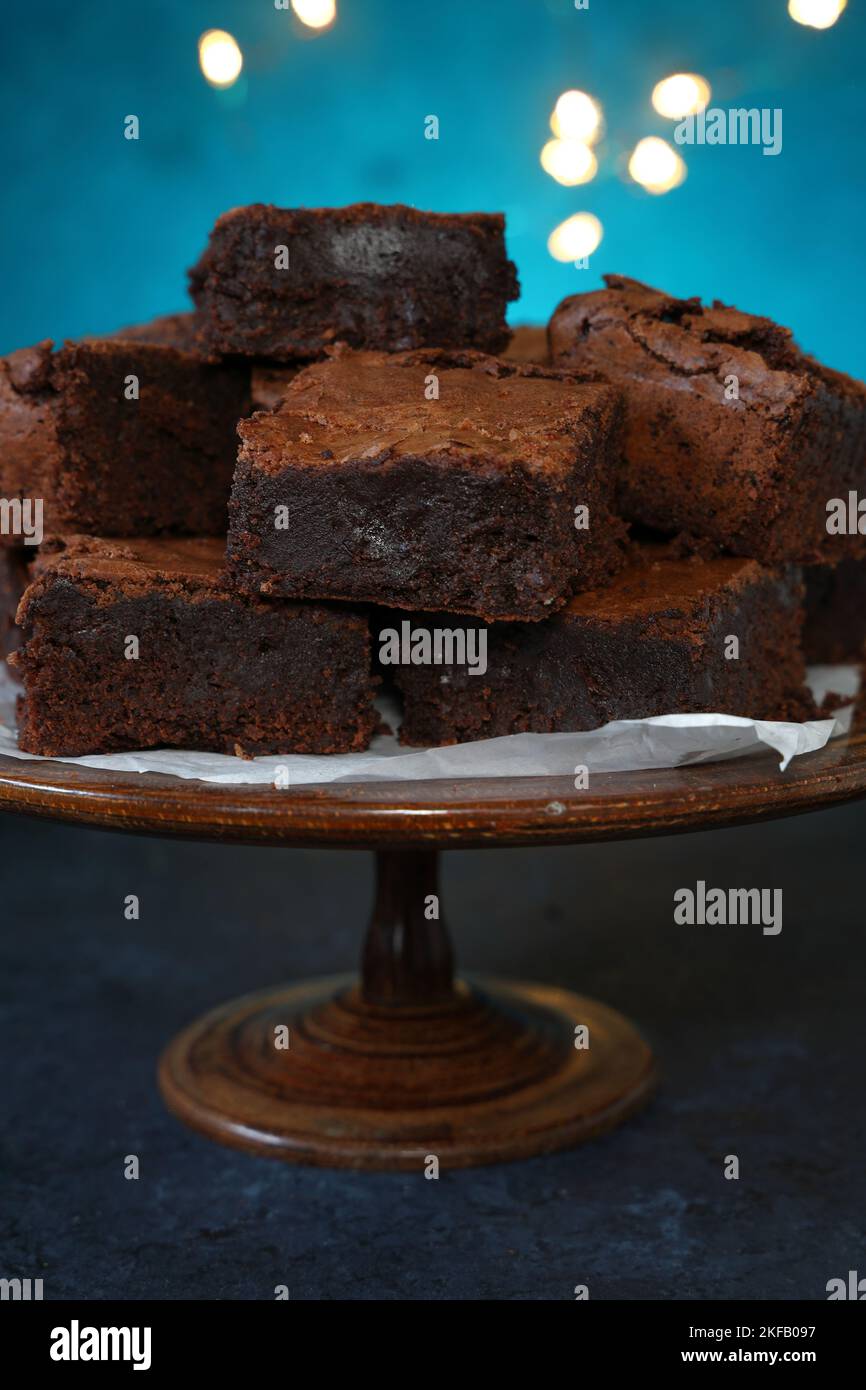 A stack of home baked rich chocolate brownies on a vintage wooden cake