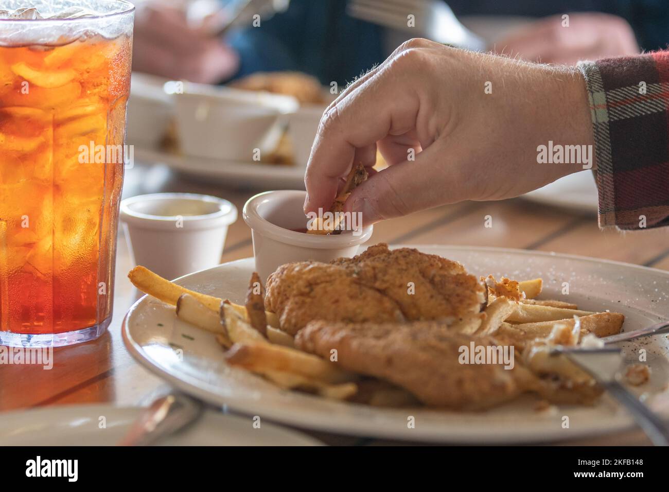 A glass of iced tea and a plate of fried catfish and french fries. Stock Photo