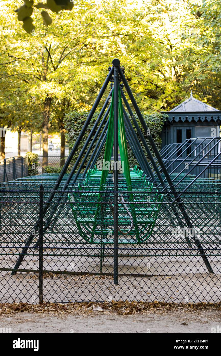 The vertical shot of fenced green swings in a row in the Luxembourg Garden of Paris Stock Photo