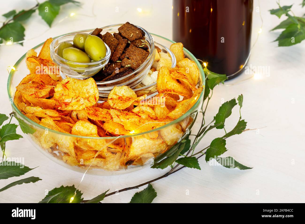 Draft beer and set of snacks on white background with green leaves
