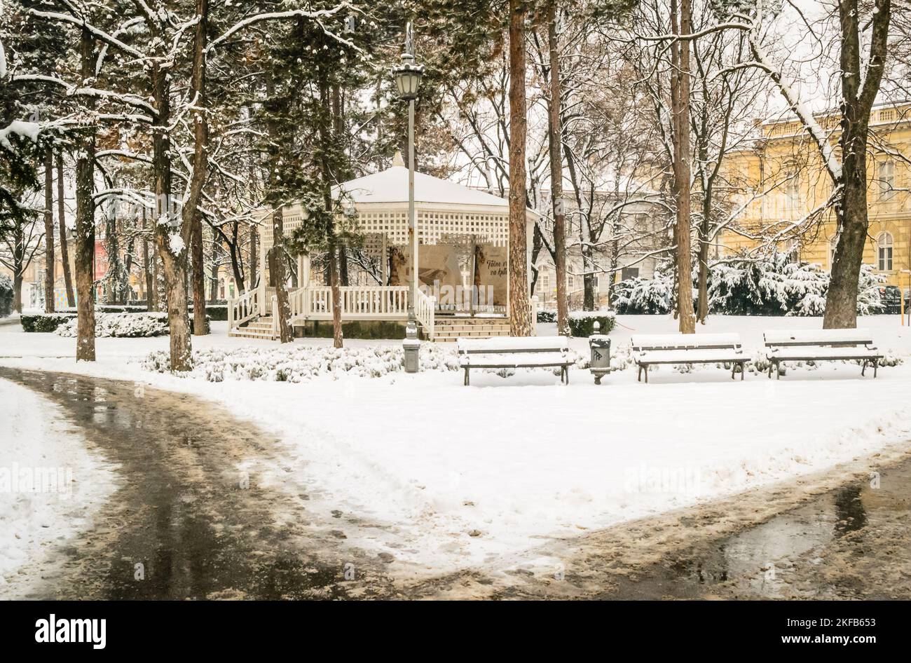 City park covered with snow. Wooden benches in the city park covered ...