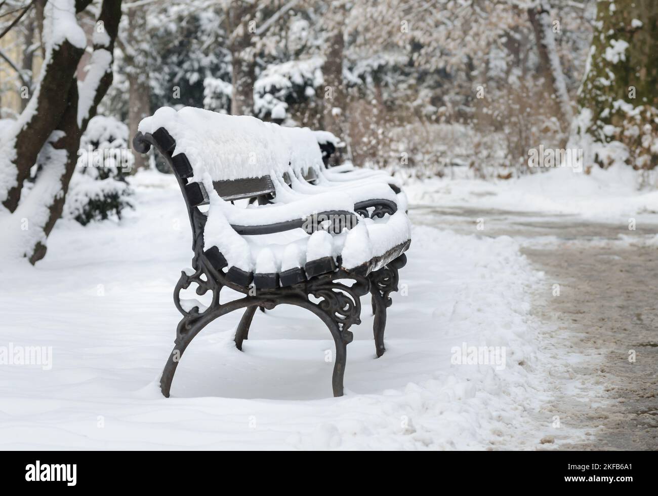 City park covered with snow. Wooden benches in the city park covered ...