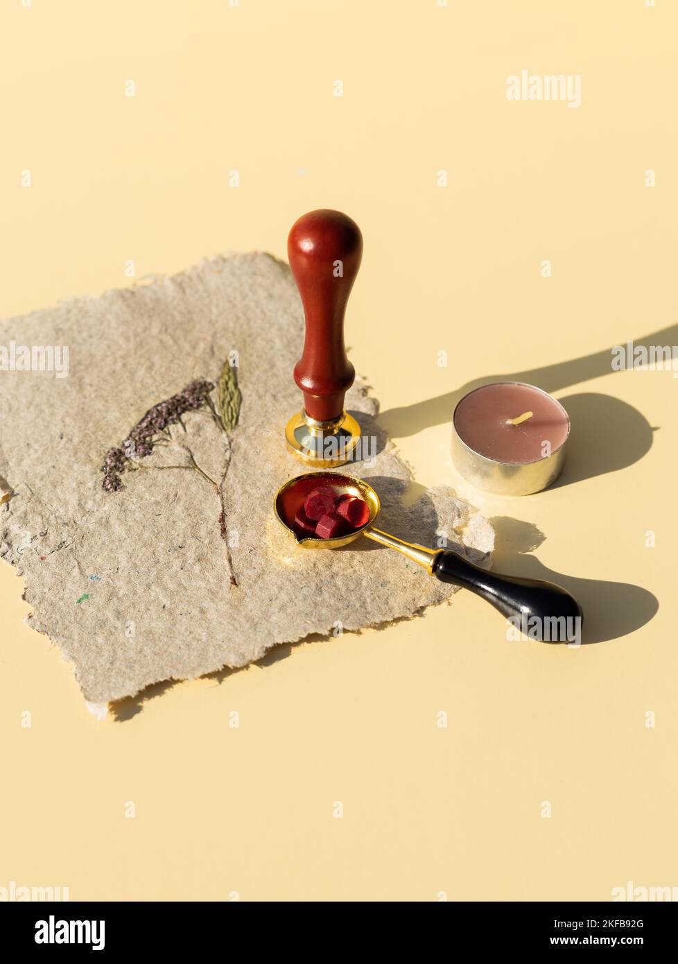 Wax printing with fire paint on homemade kraft paper with pressed dried flowers. Sealing wax