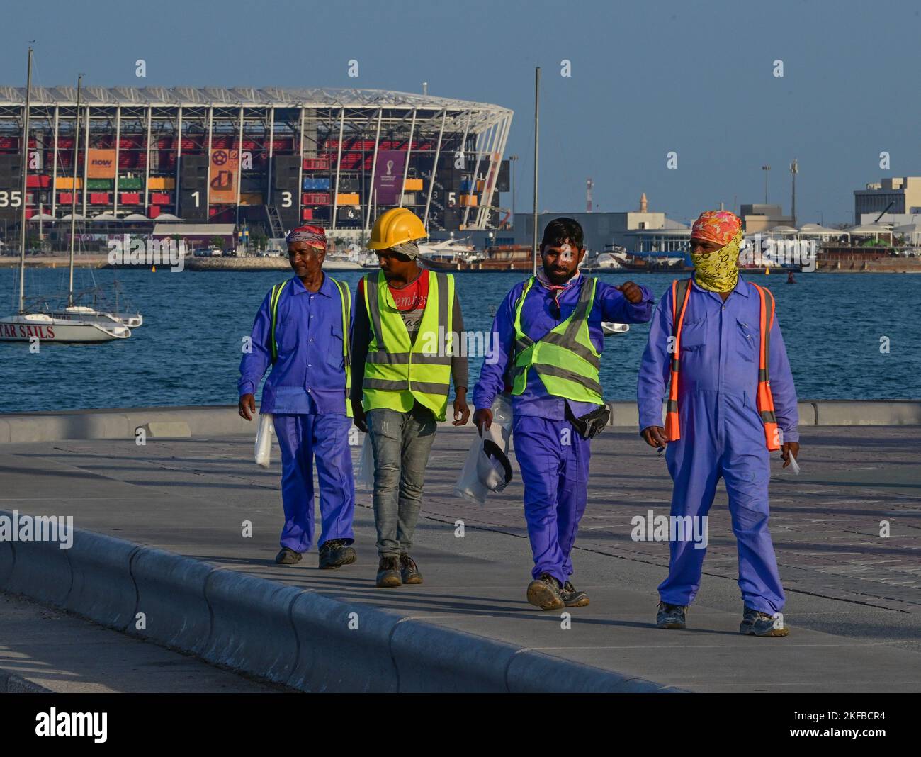 DOHA 20221116 Workers on the famous Corniche promenade in Doha with the Ras Abu Aboud Stadium in