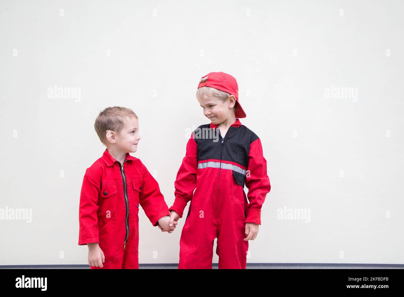 Two cute little boys in red overalls as mechanics of a car service