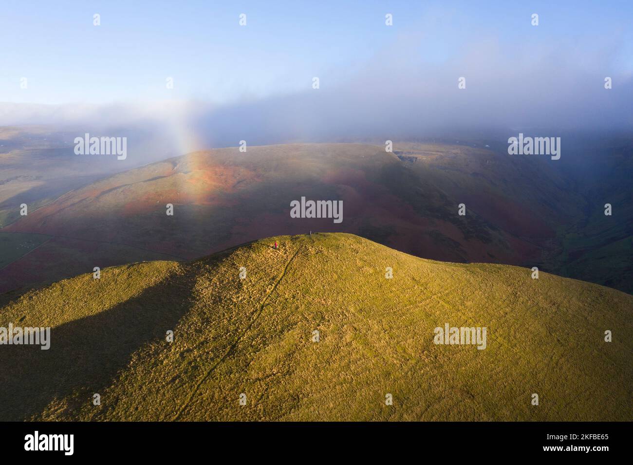 Two Walkers on the Summit Dufton Pike with a Rainbow Arcing above them, Eden Valley, Cumbria, UK Stock Photo