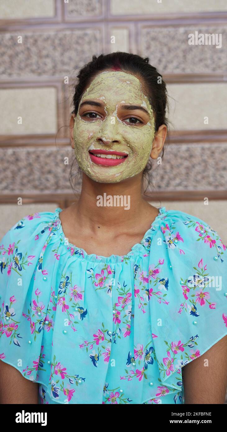 Beautiful young woman using homemade facial mask on face and relaxing