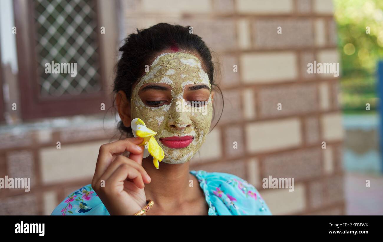 Beautiful young woman using homemade facial mask on face and relaxing at Home. Asian women with Multani Mitti and Rose Water face pack. Portrait of sp Stock Photo