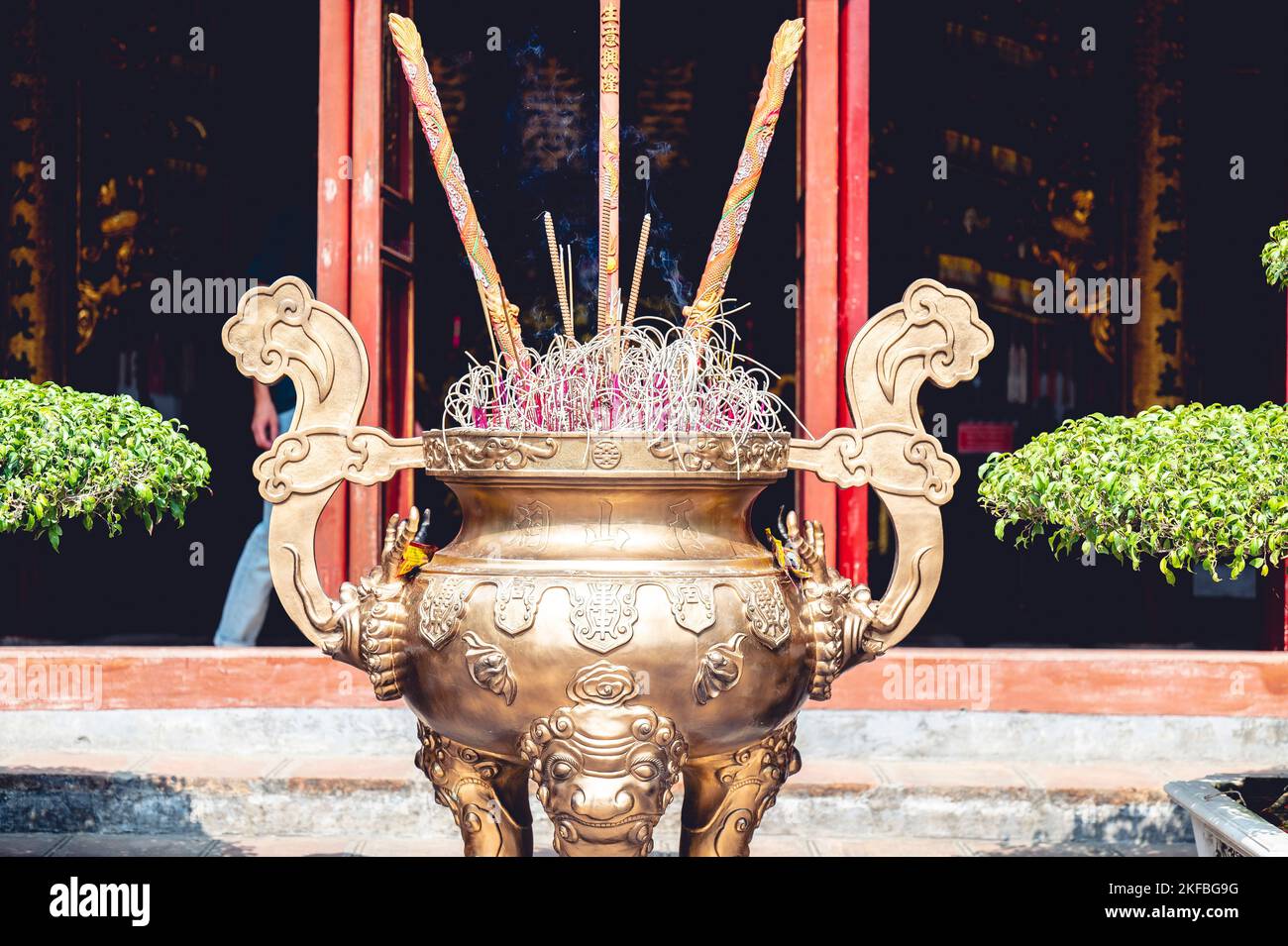 The burning incense sticks in a large ceremonial Buddhist temple urn in