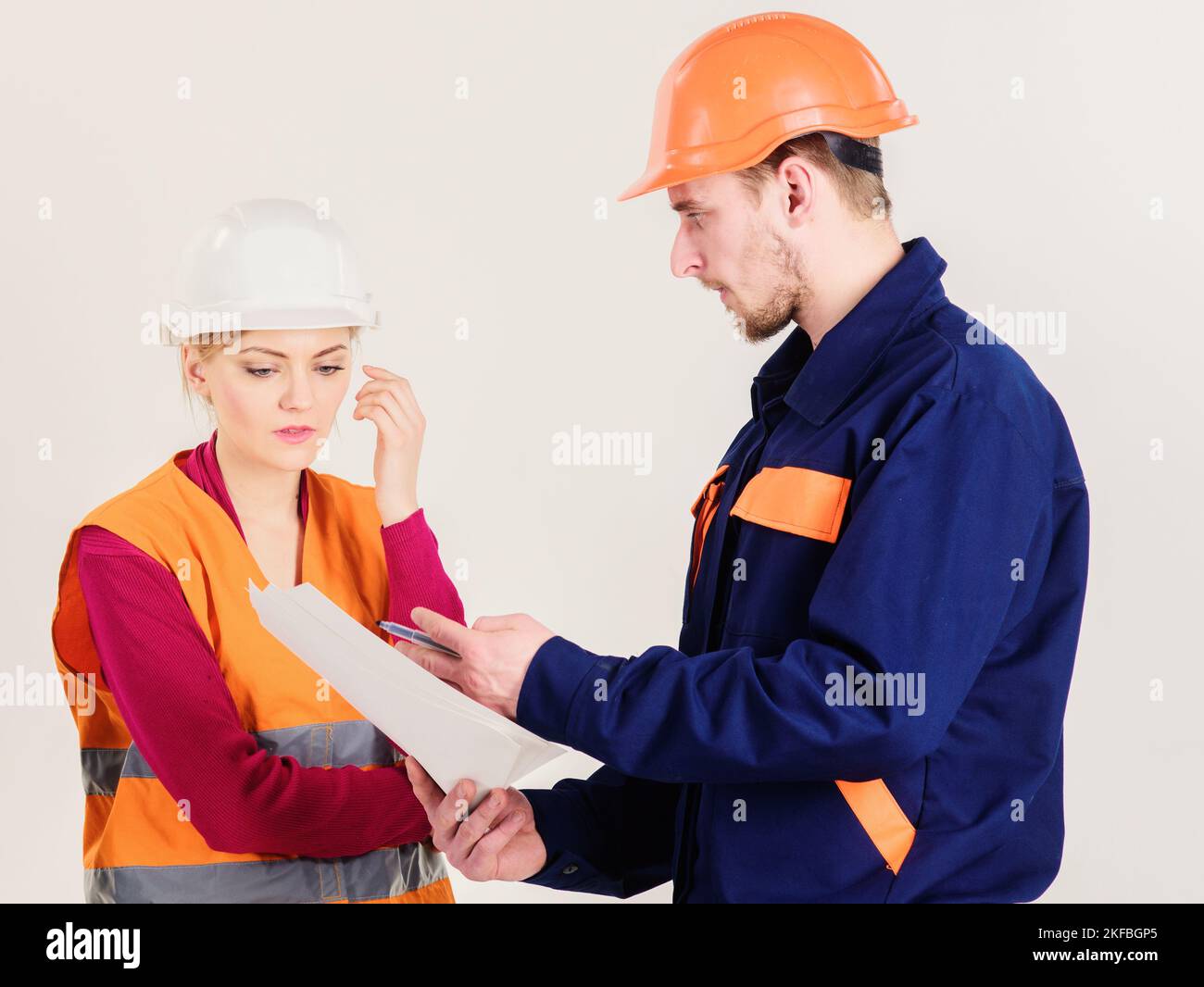 Man and woman in hard hats, uniform looks at blueprint Stock Photo - Alamy