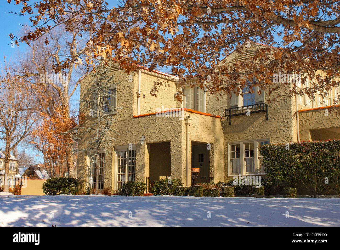 Entrance of landscaped stucco two story house with snow on the ground in upscale neighborhood Stock Photo