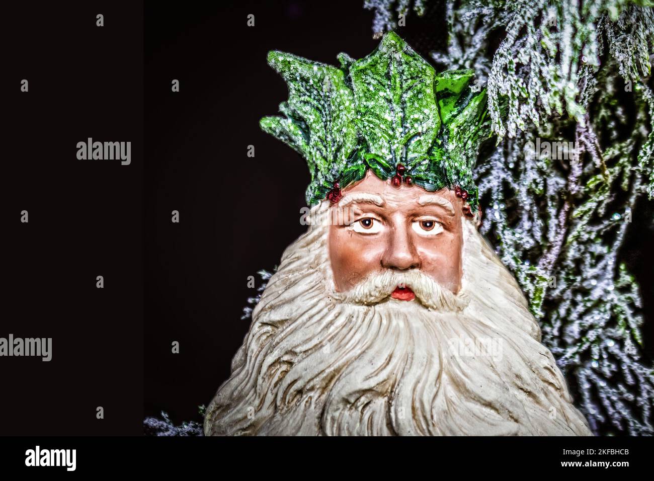 Father Christmas - The Holly King - Ceramic Christmas tree decoration with sparkly bokeh greenery background- room for copy. Stock Photo