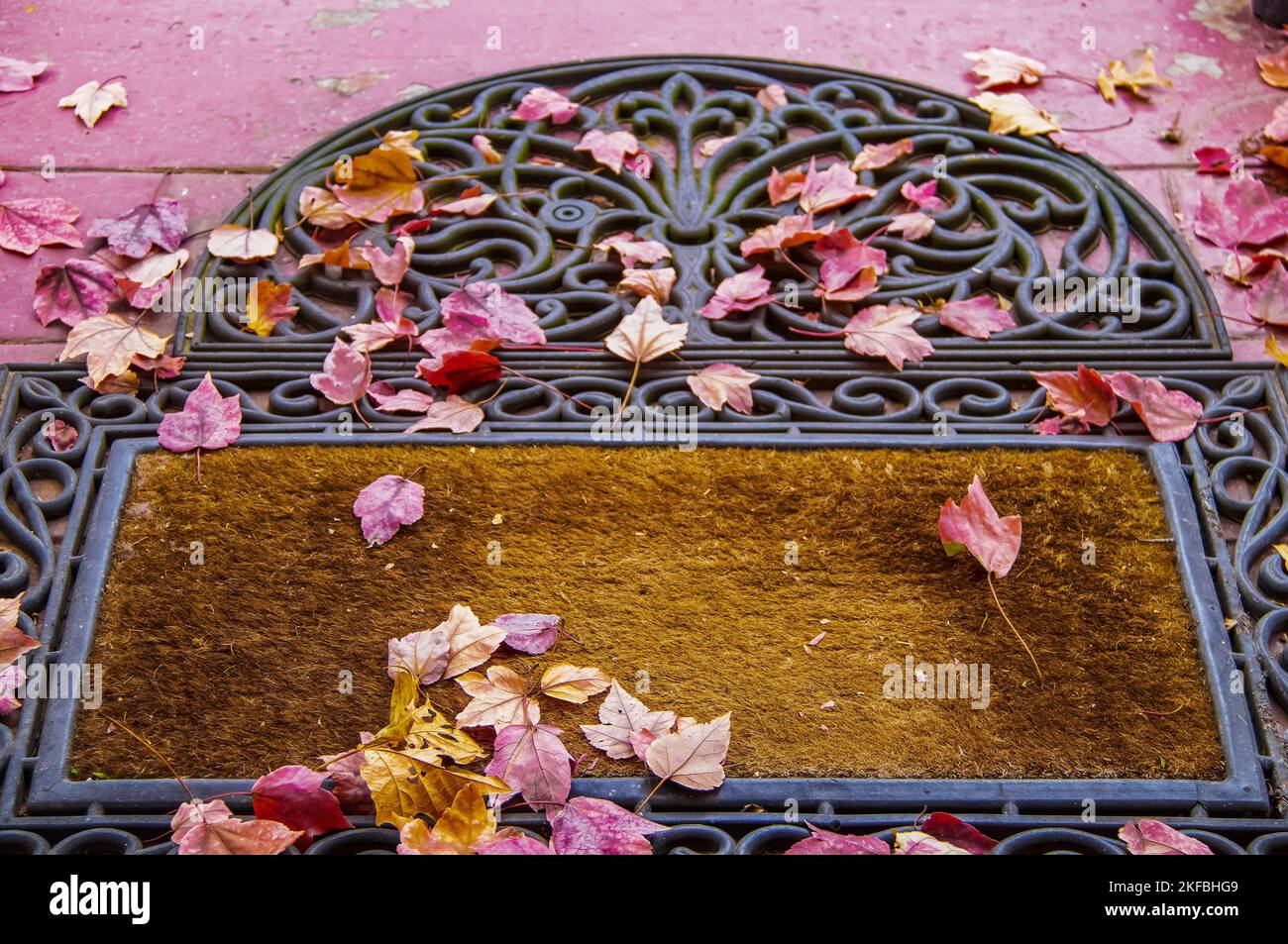 Front door mat with colorful fall leaves - focus on foreground. Stock Photo
